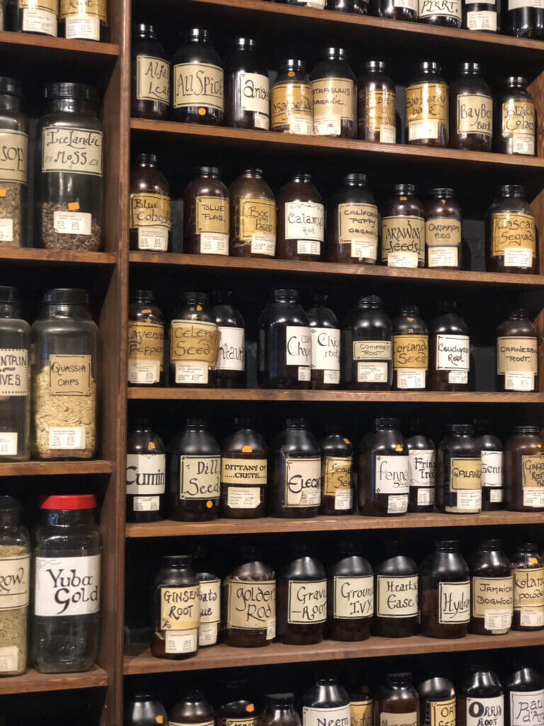 Shelves filled with numerous glass bottles labeled with various names, suggesting a collection of chemicals or apothecary ingredients.