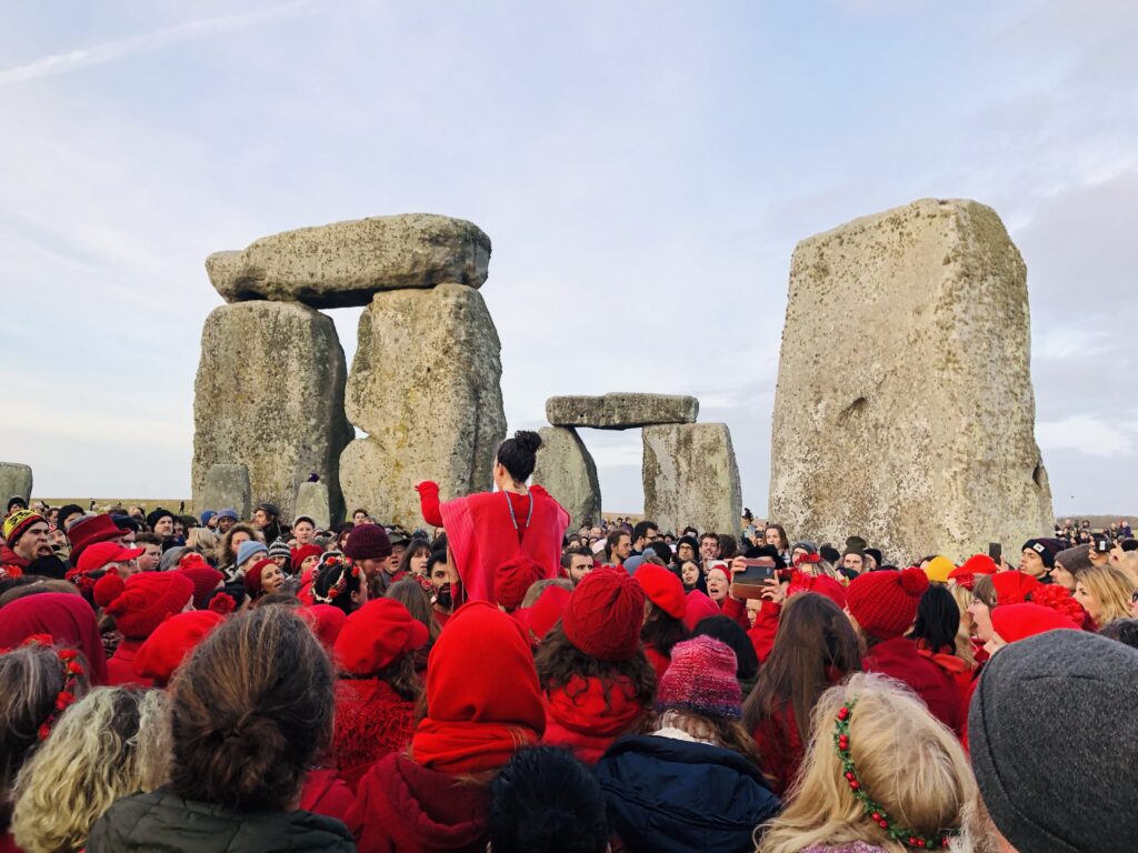 The image shows a crowd gathering at Stonehenge.